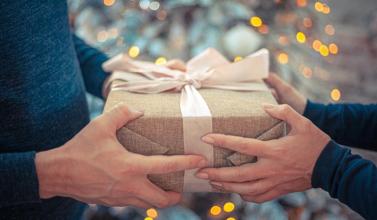 mani uomo e donna che si scambiano regalo di Natale